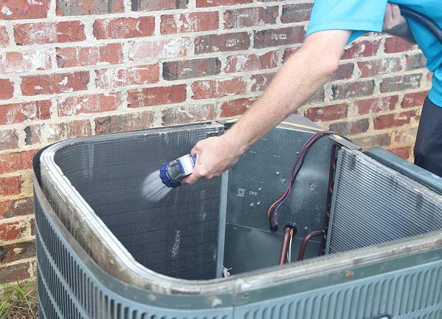 Technician cleaning AC coils with water