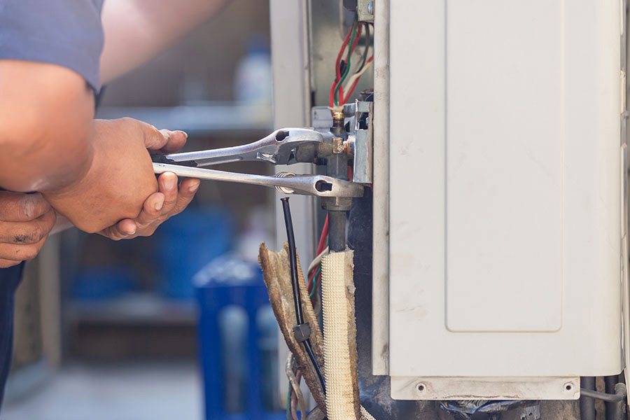 Technician repairing AC unit with wrench